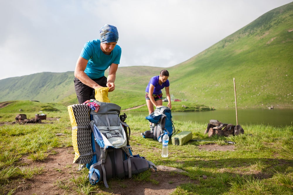 two hikers pack their bags at the campsite