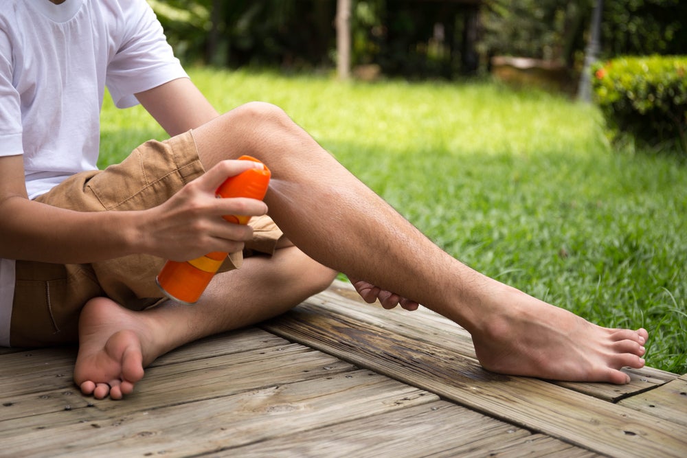 a boy spraying his leg with spray