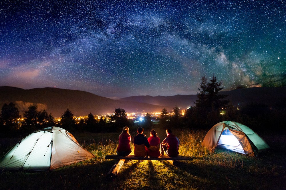 a group of campers near two tents at night