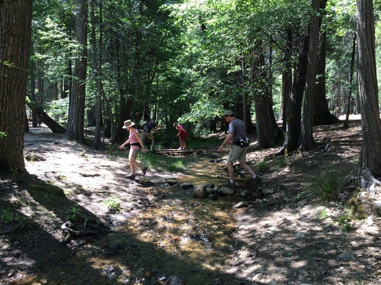 People walking across a river at Upper Pines Campground.