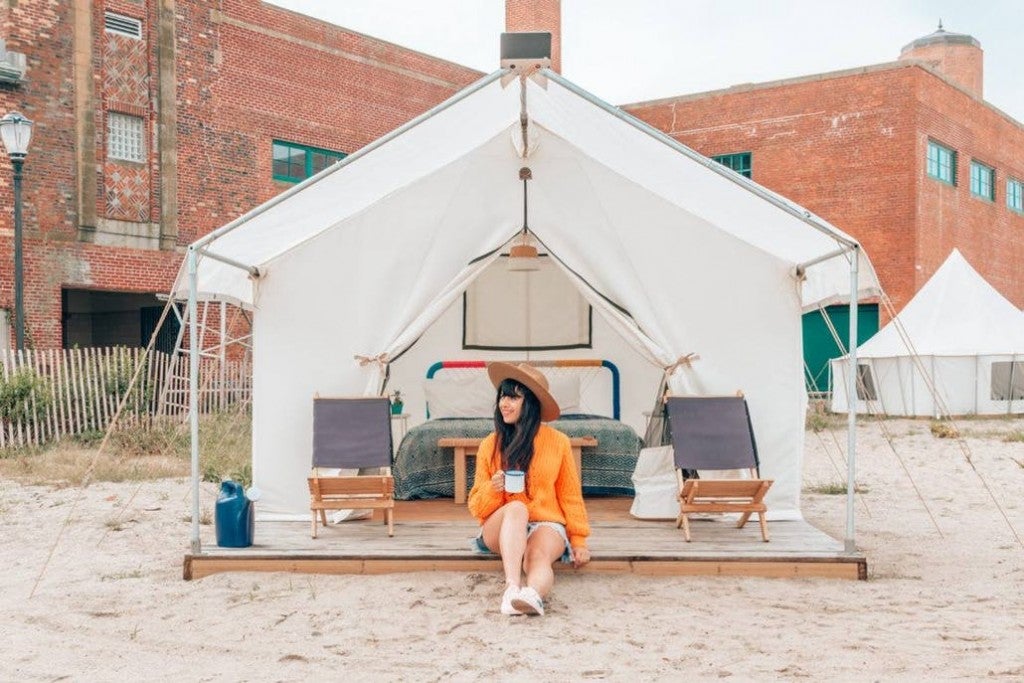 a woman sitting in a camping tent on a beach in new york city