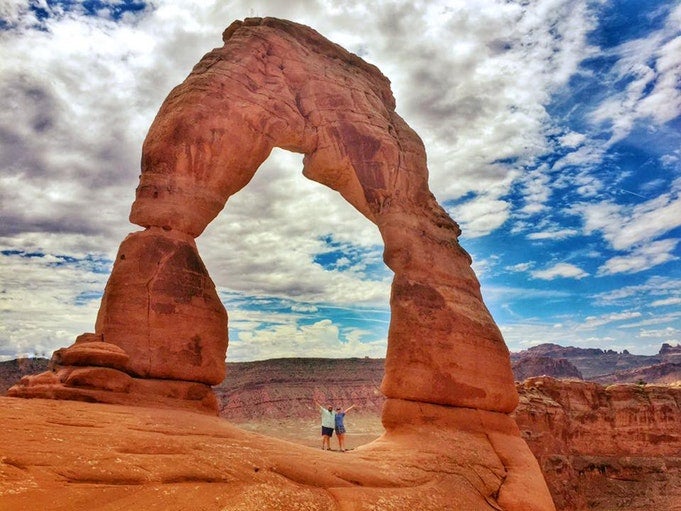 hikers under delicate arch in Arches National Park