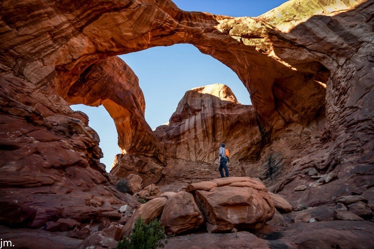 Hiker under Double O Arch in Arches National Park