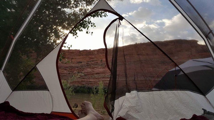 feet hanging from tent while camping in arches national park