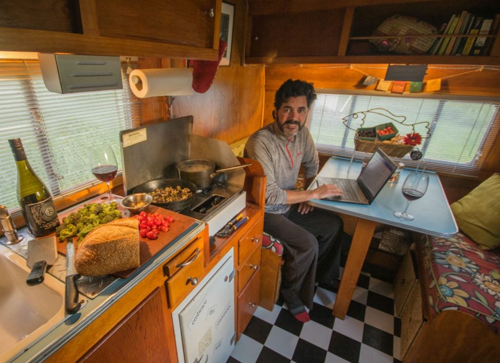 a man sitting at a table in an RV on a laptop