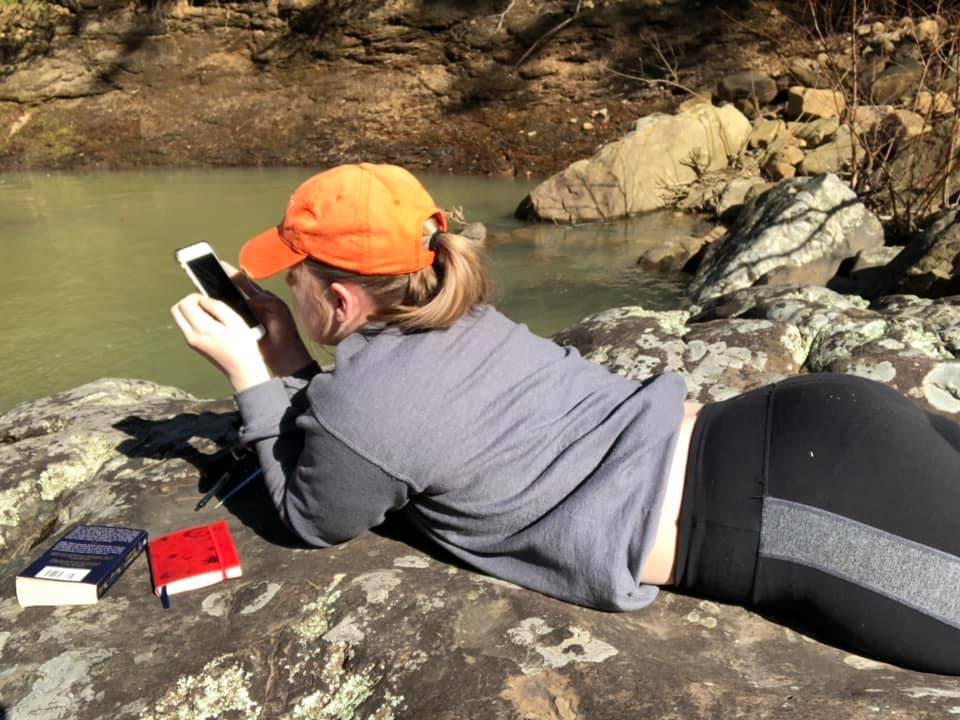 woman lying on her stomach looking at her phone