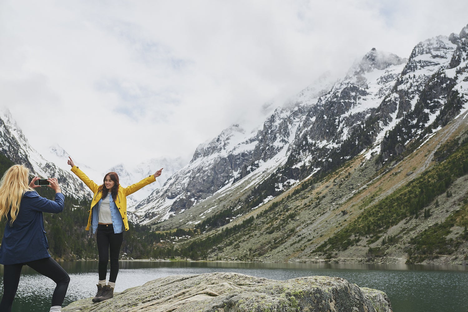 girl photographs friend in front of an alpine lake on leave no trace trip