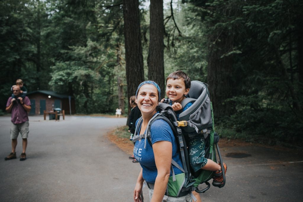 hiking family smiles with toddlers in back carriers, via hike it baby