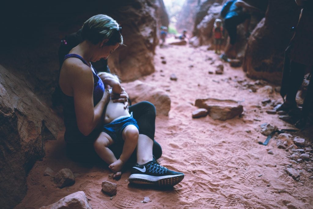 mother breastfeeding young son on red dusty hiking path, via hike it baby