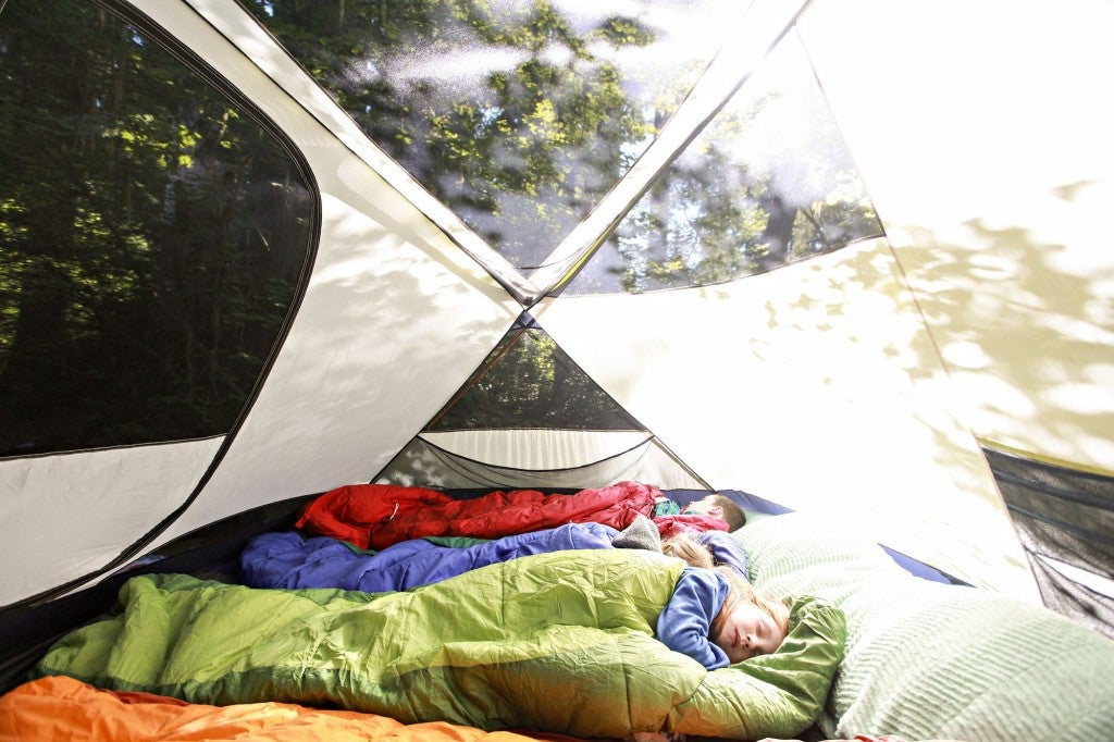three children sleeping in tent during daytime