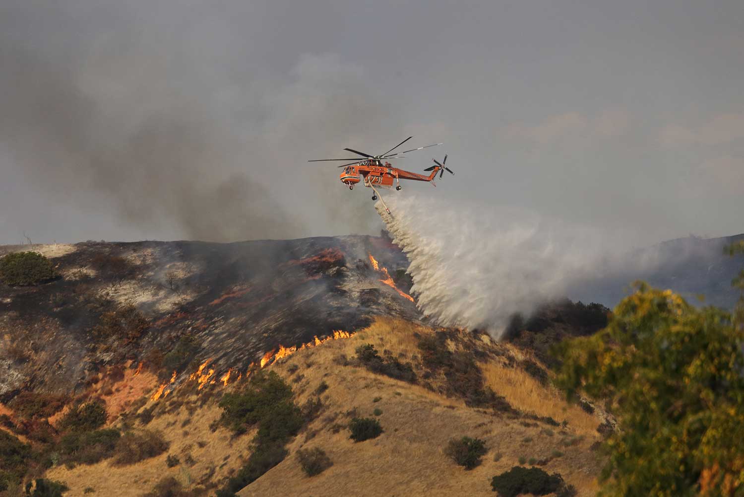 helicopter dropping fire retardant to help fire victims in california