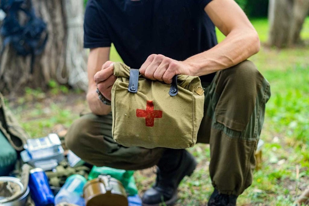 Person outdoors holding a first aid kit.