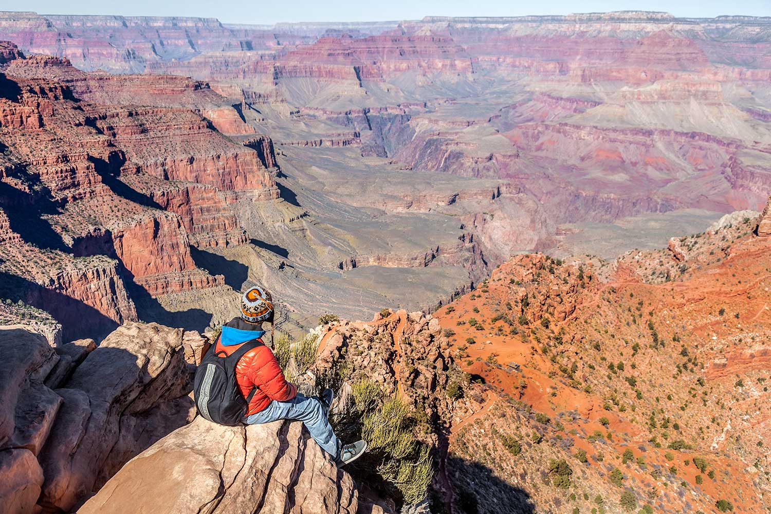 person sitting on rock overlooking the grand canyon