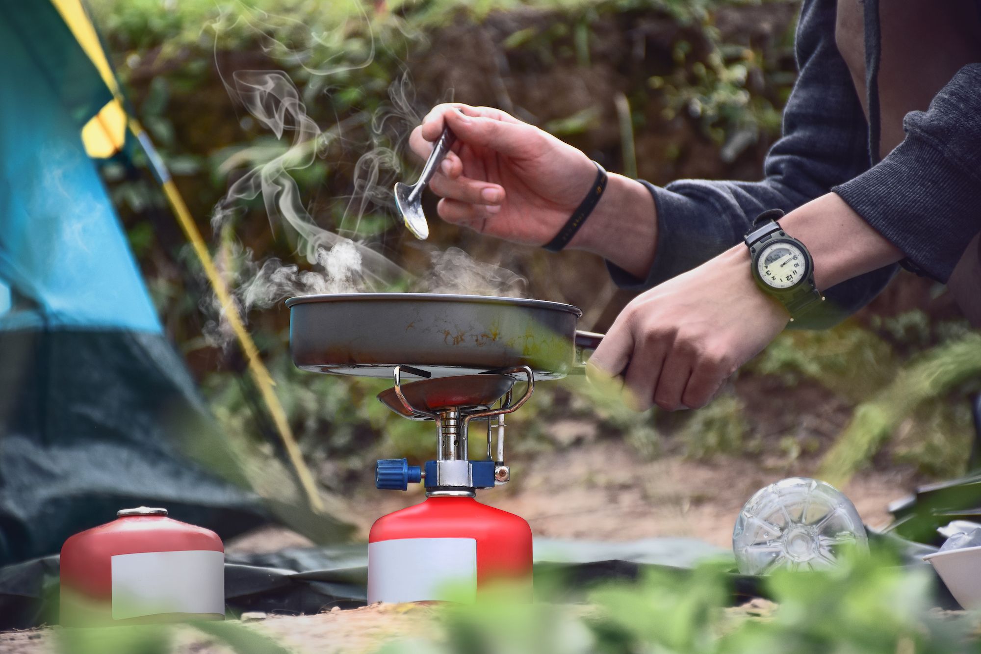 camper making breakfast hash in campsite on portable stove