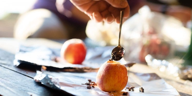 stuffing chocolate into campfire baked apples with a spoon