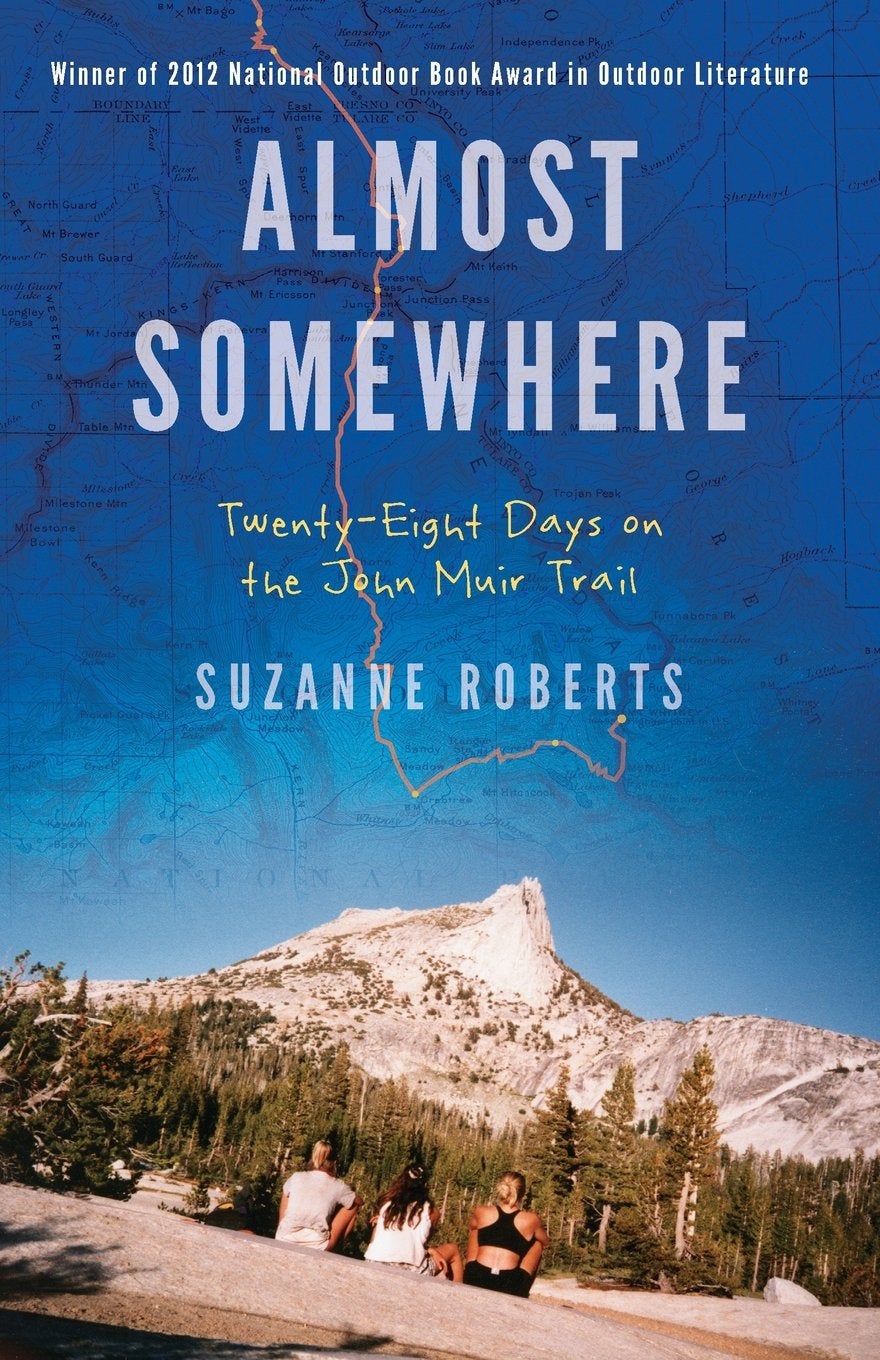 women sitting on the ground below a mountain on the cover of a book