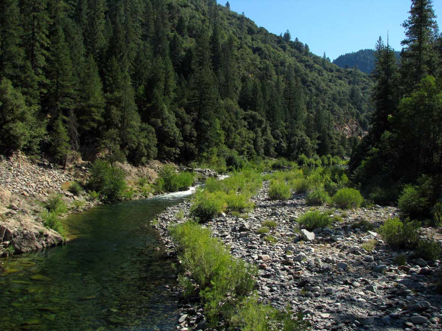 a clear river in oregon running through a mountain pass