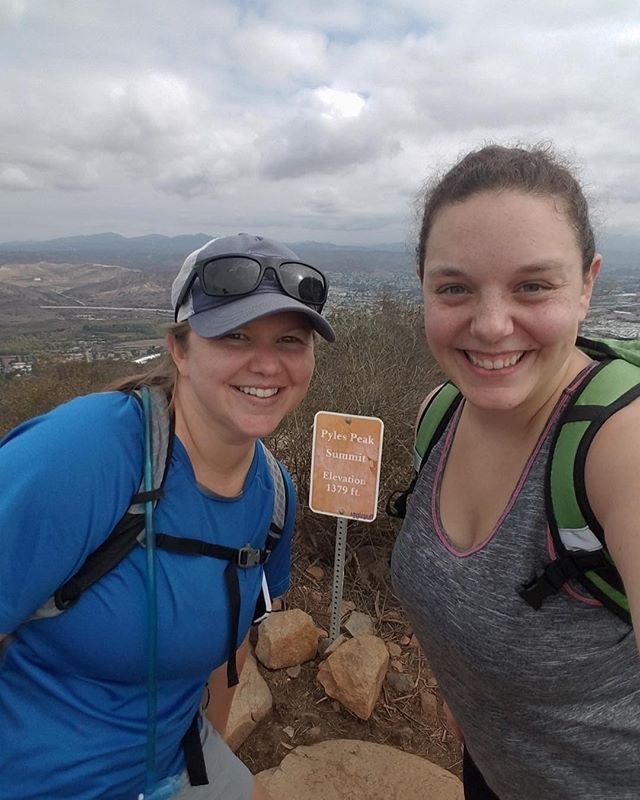 two female hikers pose for a selfie at the summit of pyles peak