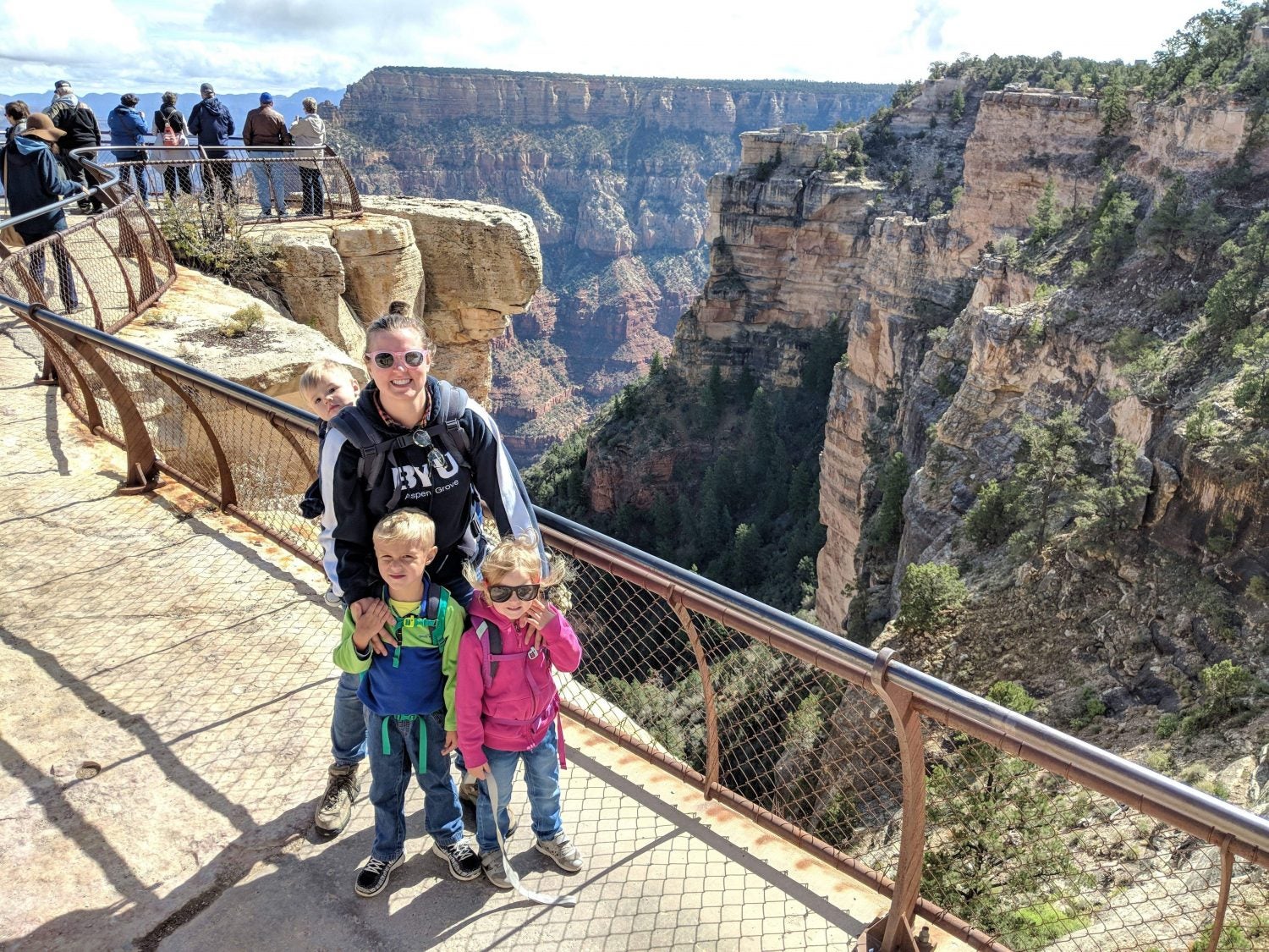 a mother and her two children pose for the camera at the edge of a canyon