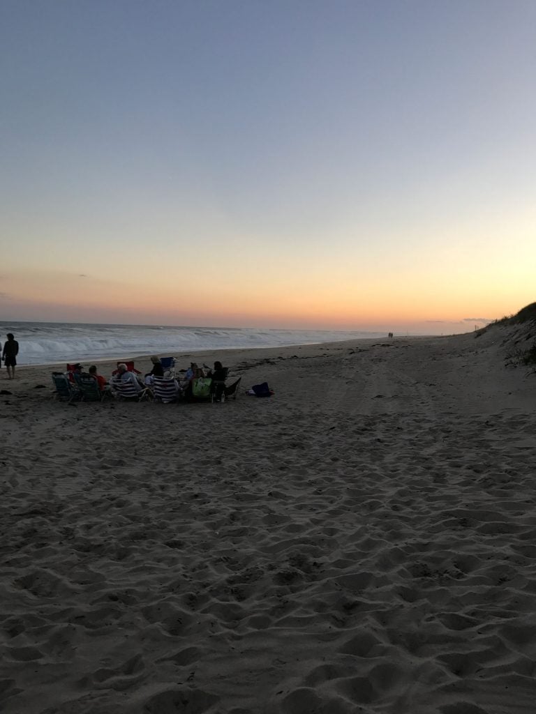 Campers relax on the beach of Hither Hills State Park during sunset.