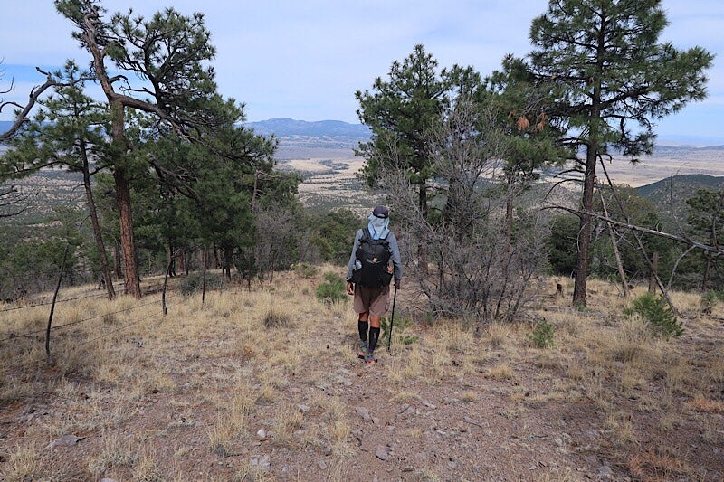 thru hiker treks downhill near the continental divide trail at dusk