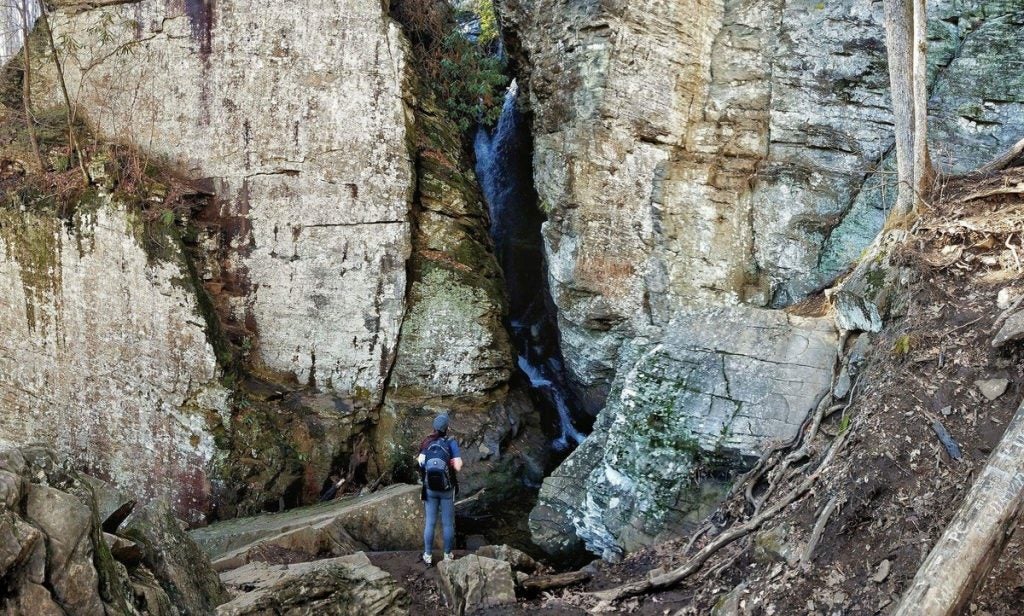 hiker stands below first tier of raven cliff falls
