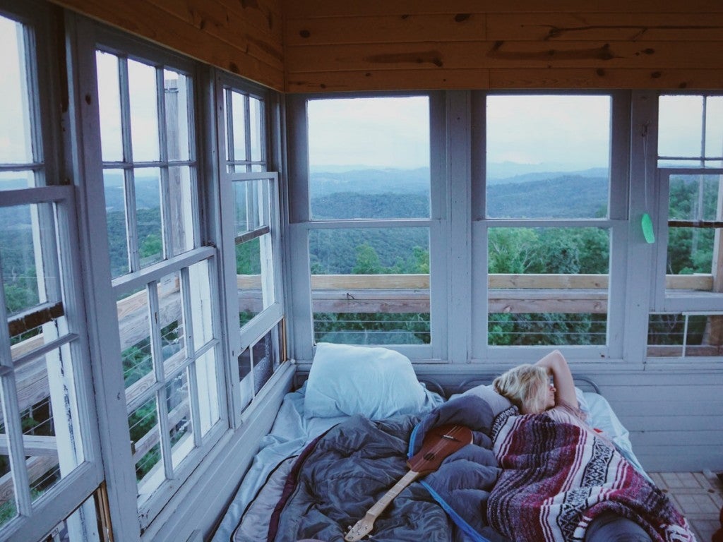 visitor sleeping in the fire tower with panoramic views out every window