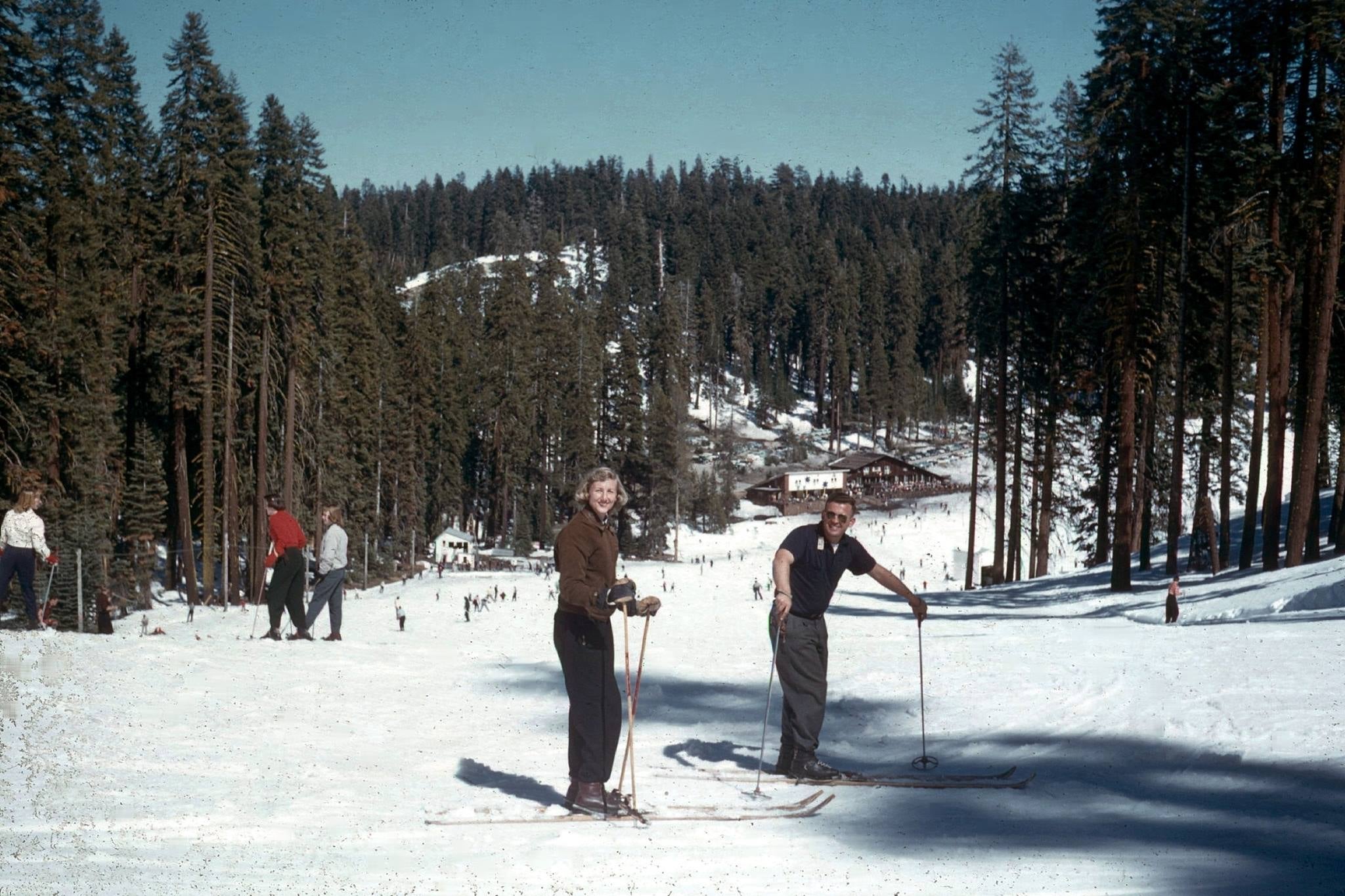 vintage photo of skiers in the foreground with a lodge in the background, badger pass circa 1950