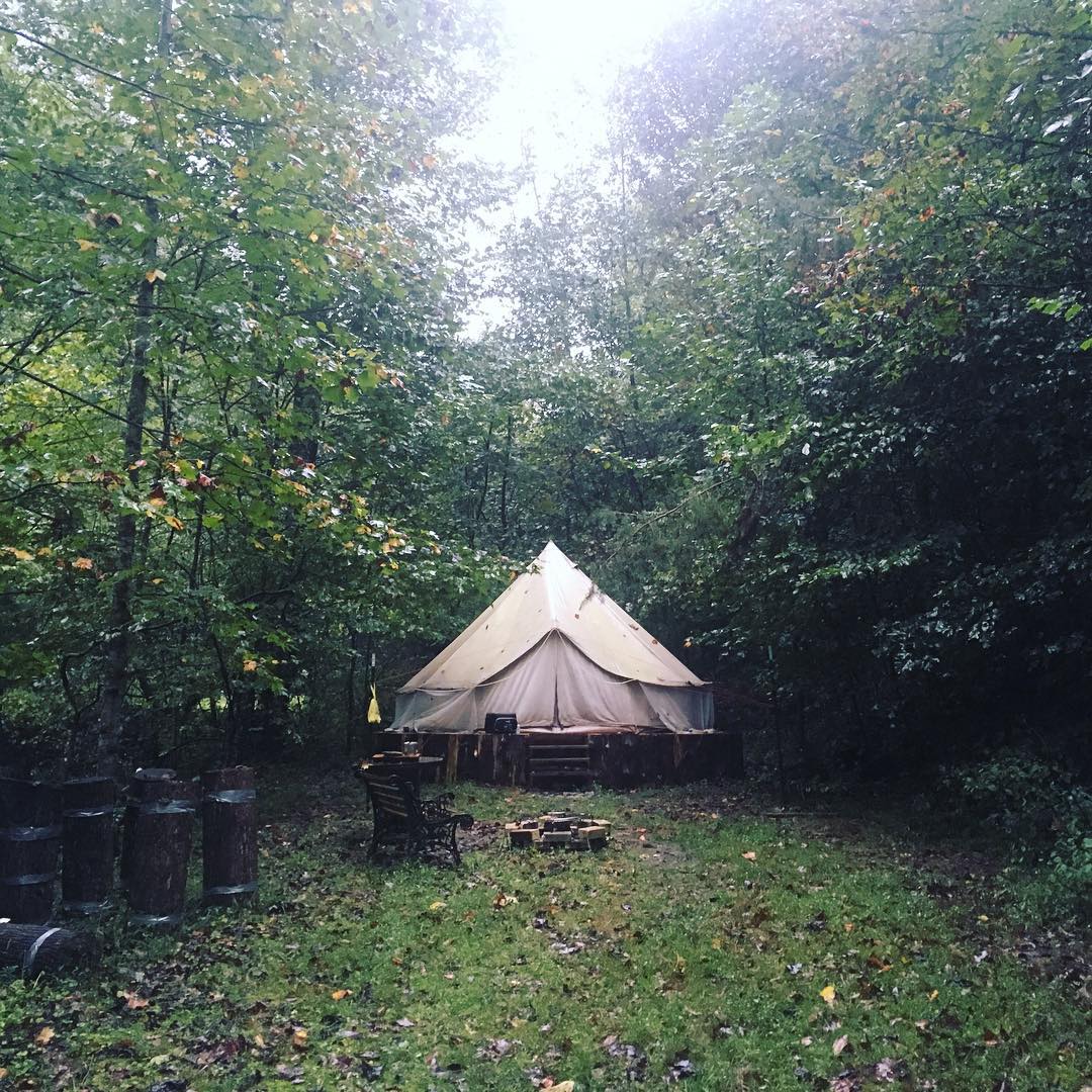 large white glamping tent on a platform surrounded by trees