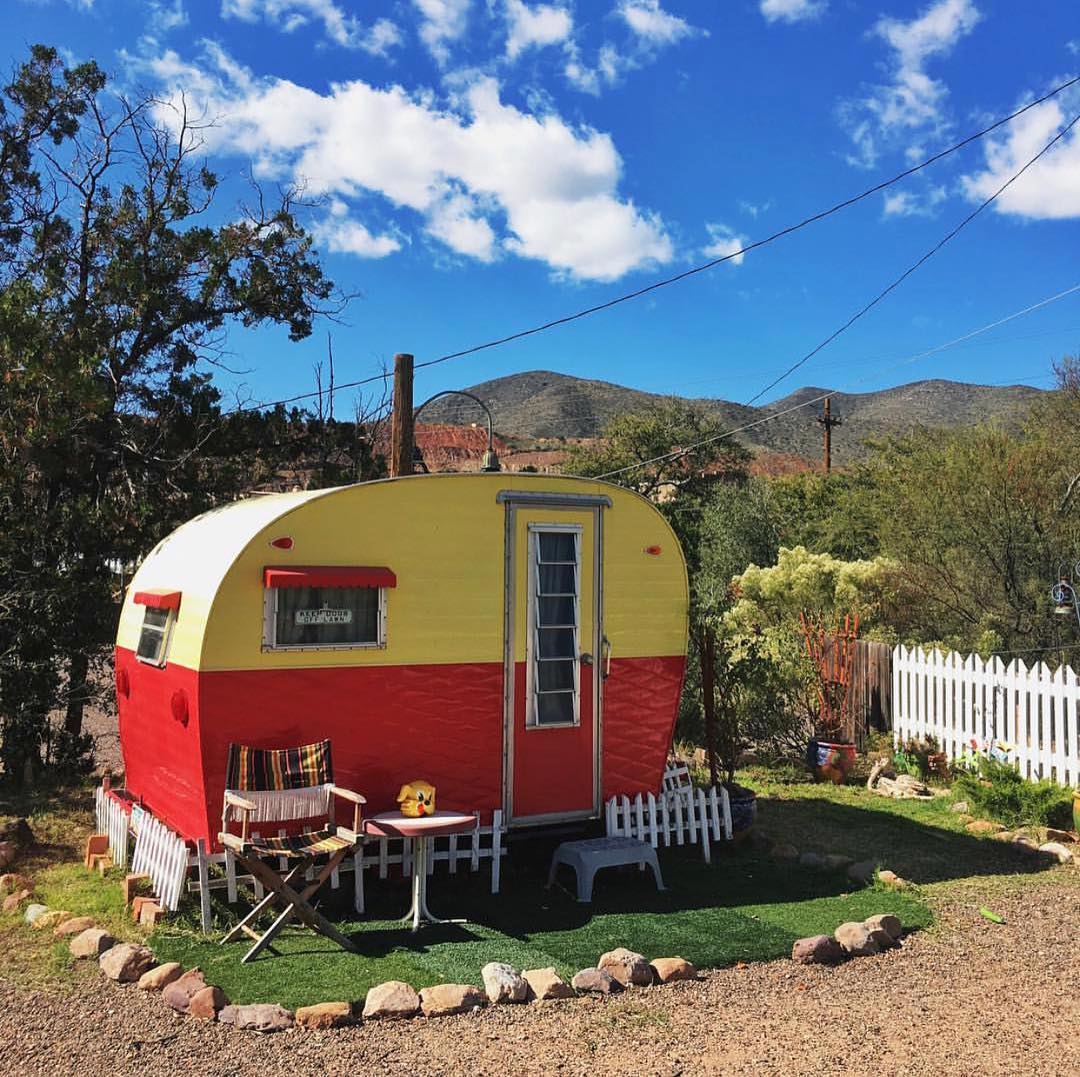 a vintage red and yellow trailer with mountains in the background