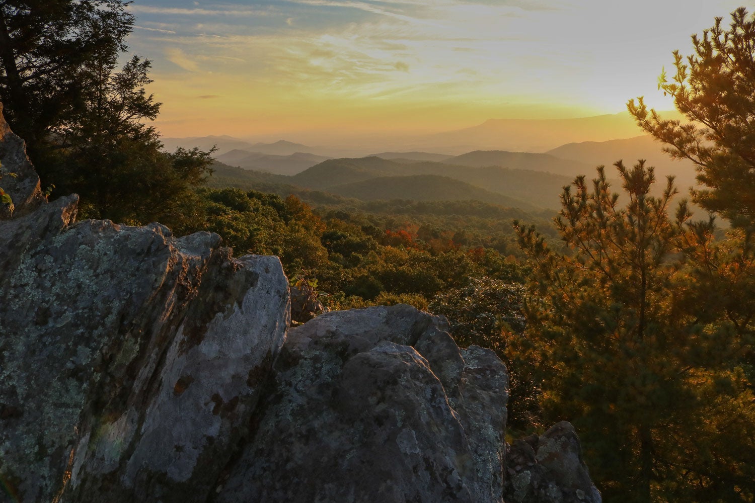 rocks and trees frame layered hill at sunset from The Point Overlook in shenandoah national park