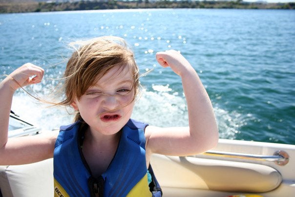 Little girl flexes her muscles on a boat in Wisconsin