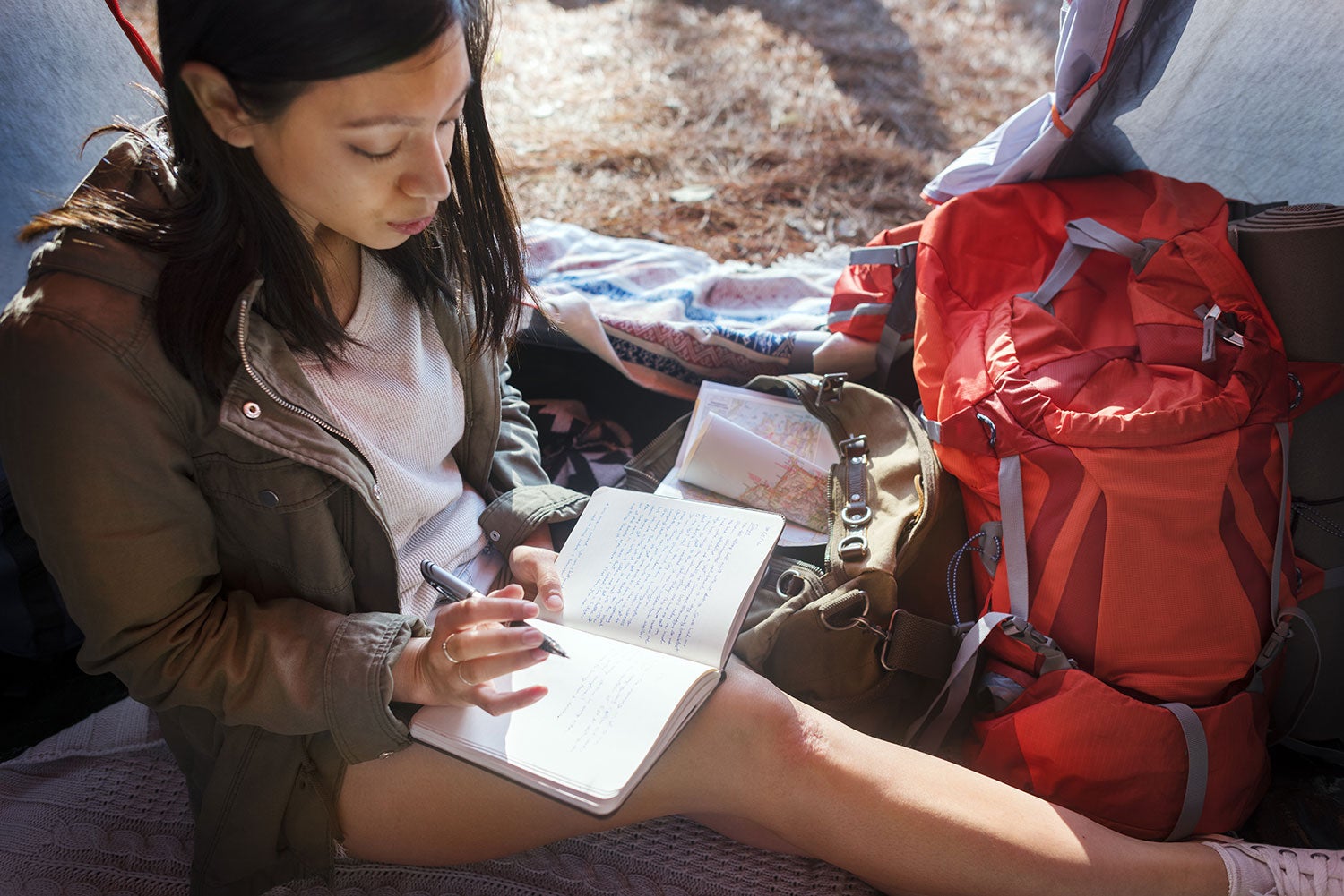 woman writing in her camping journal in her tent