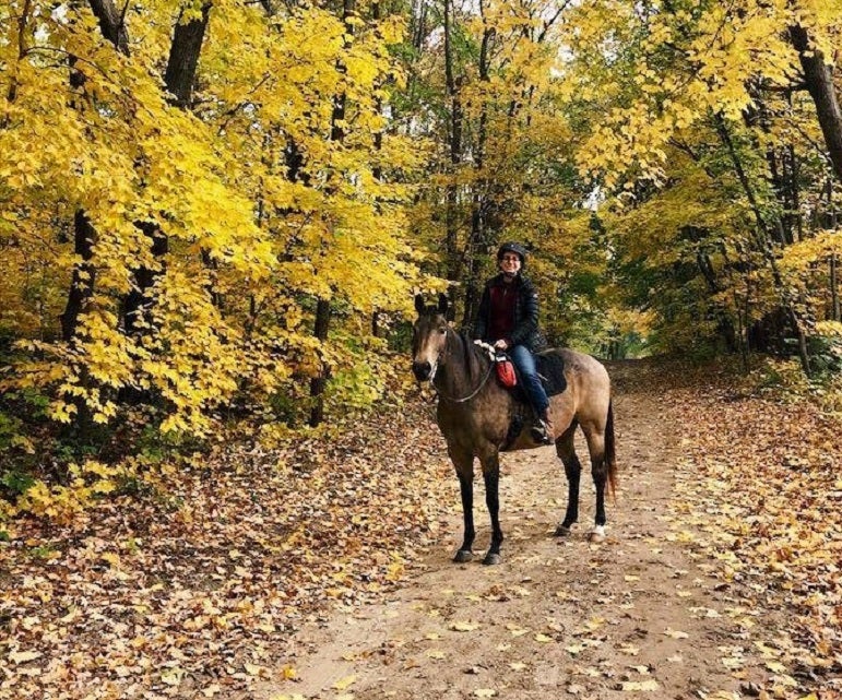 woman on horse in forest of yellow Fall foliage