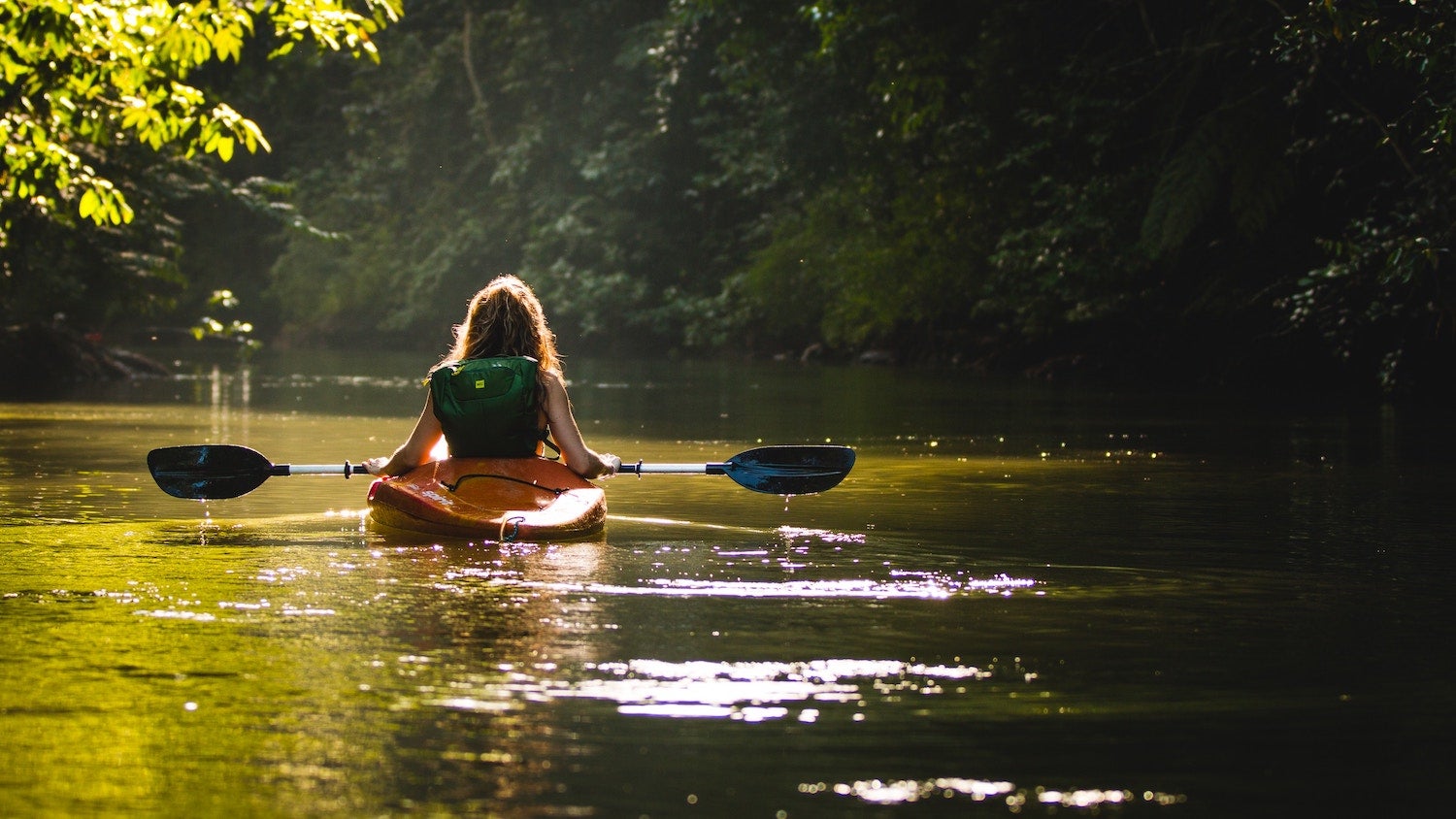 view from behind of a woman kayaking in a nc waterway