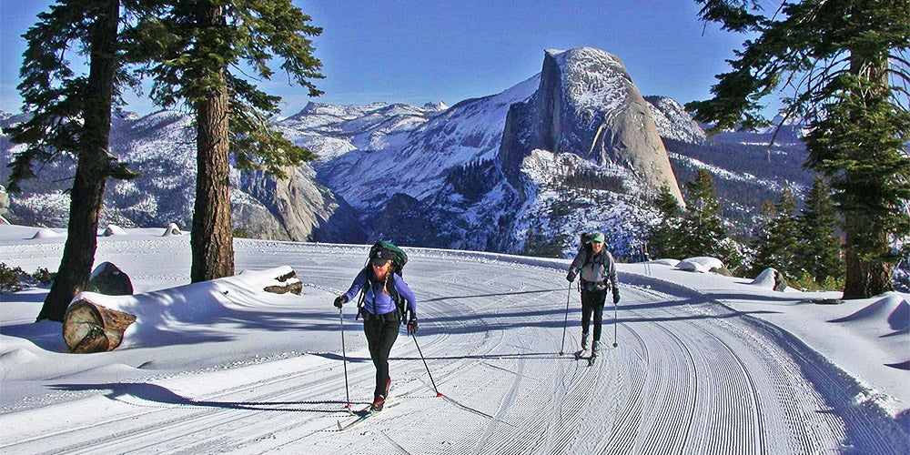 two cross country skiers on badger pass trail with half dome in background