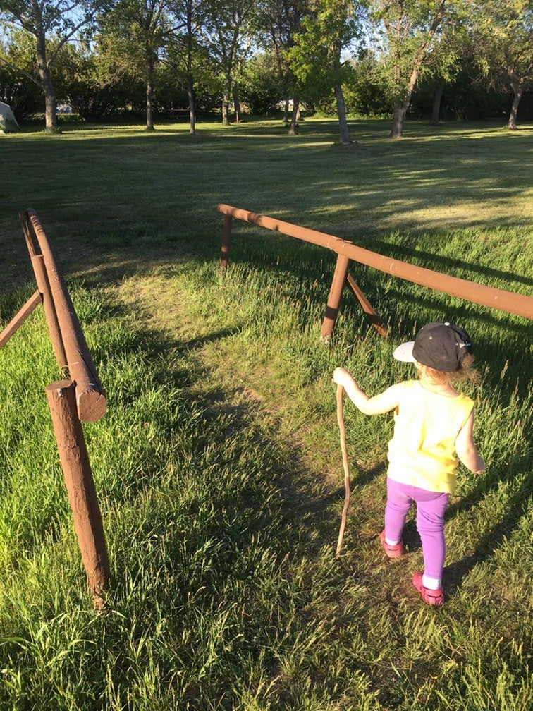 young girl with walking stick travels a grassy path in fort stevens state park