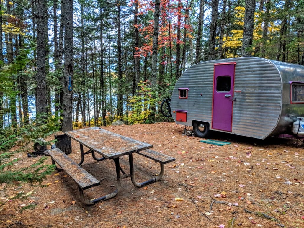 vintage camper trailer in wooded autumn campsite