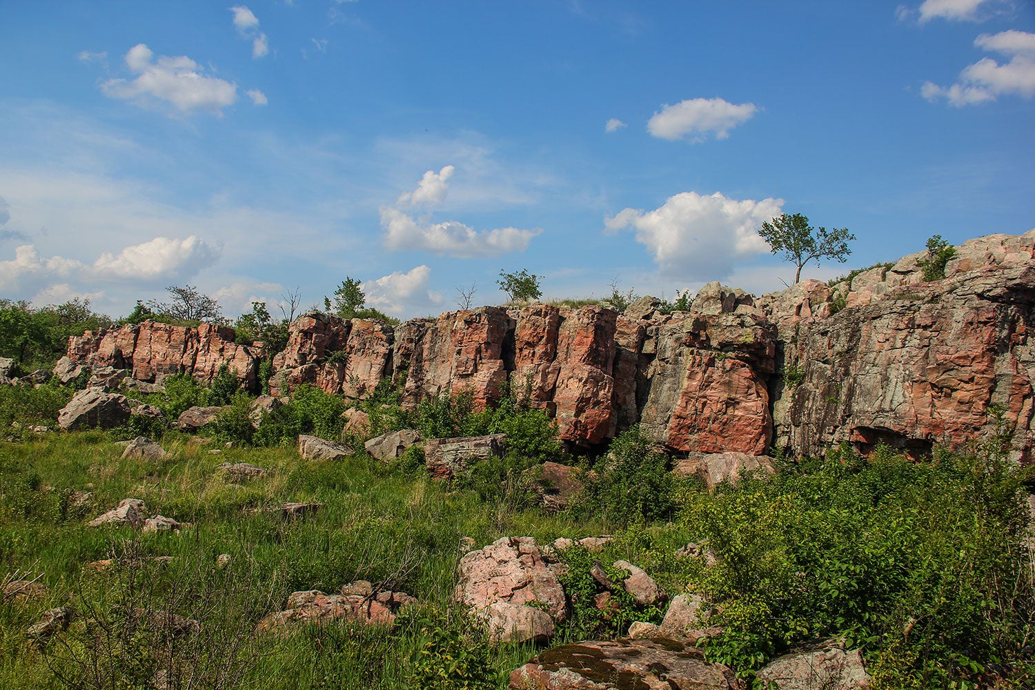 Cliffs in a grass field under a blue sky.