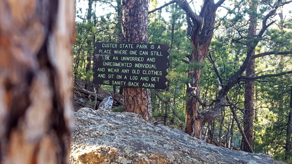 a sign for custer state park posted on a tree