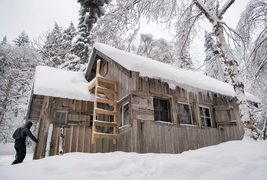 a wooden vermont camping cabin covered in snow during the day