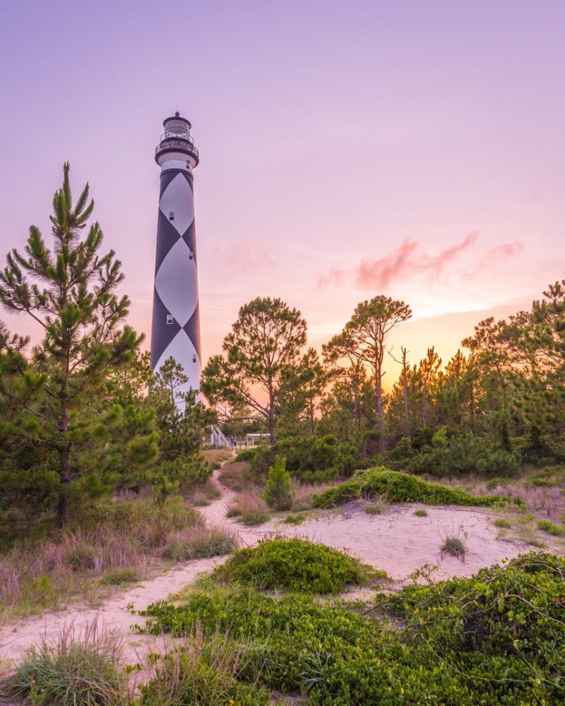 a lighthouse near grassy sand dunes in north carolina's cape lookout national seashore