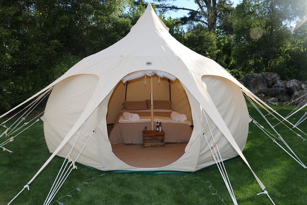 lotus belle glamping tent set up with furnishings in a lush field