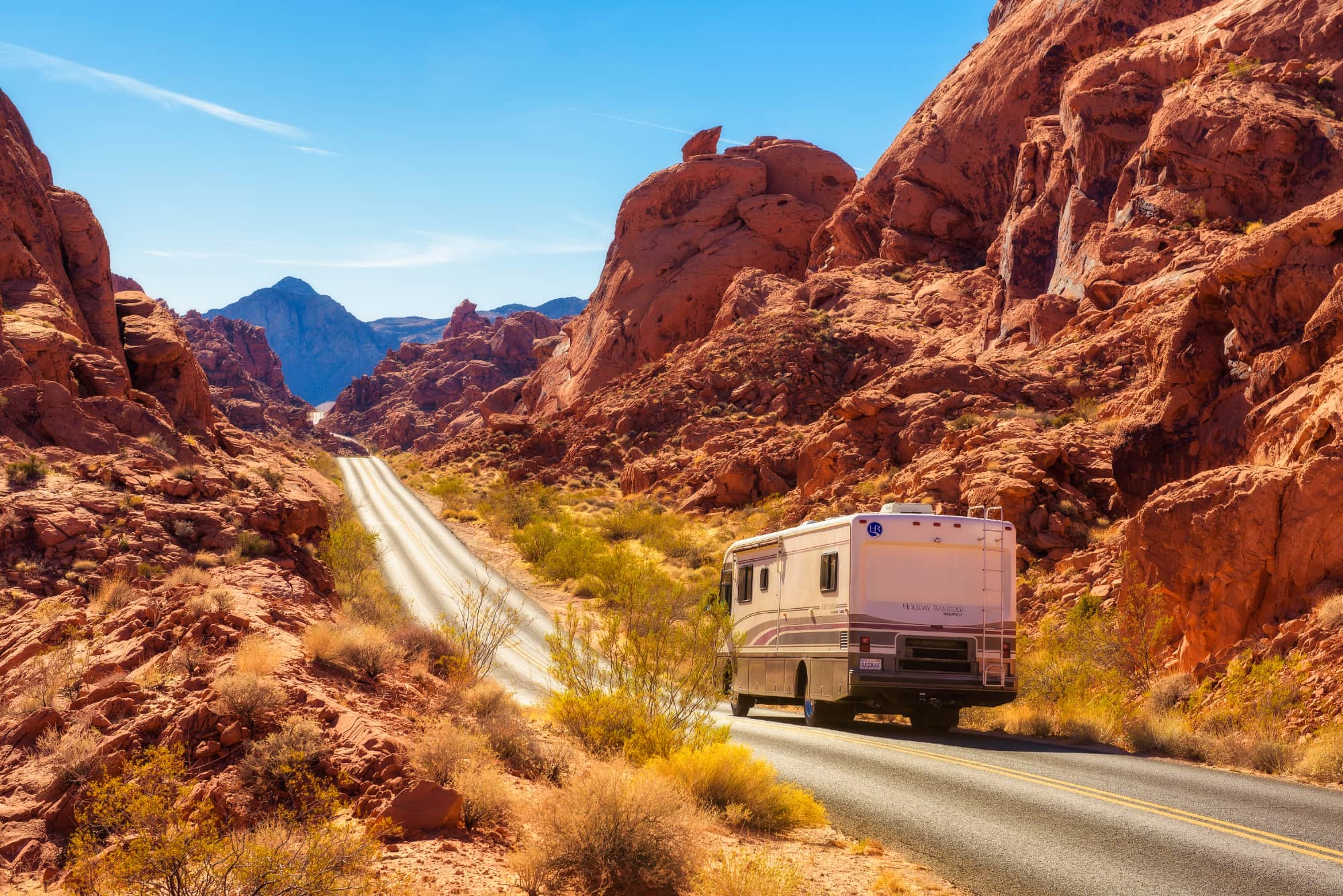rv driving down road in a red rock canyon