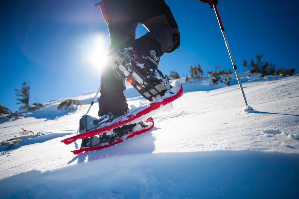 ground view of man in snowshoes with trekking poles is the snow in the mountains.