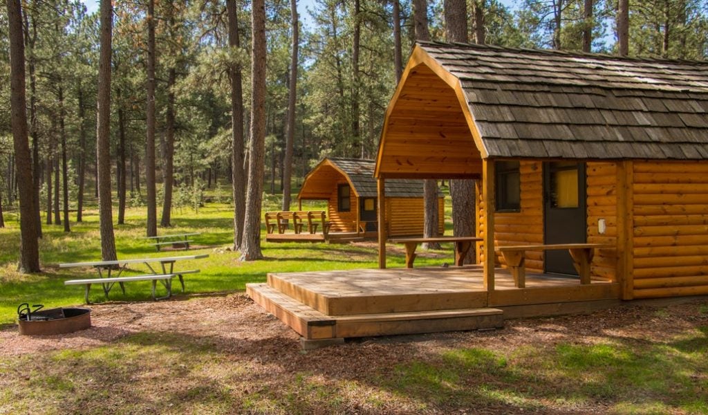a cluster of cabins in the forest with picnic tables and fire pits at blue bell lodge