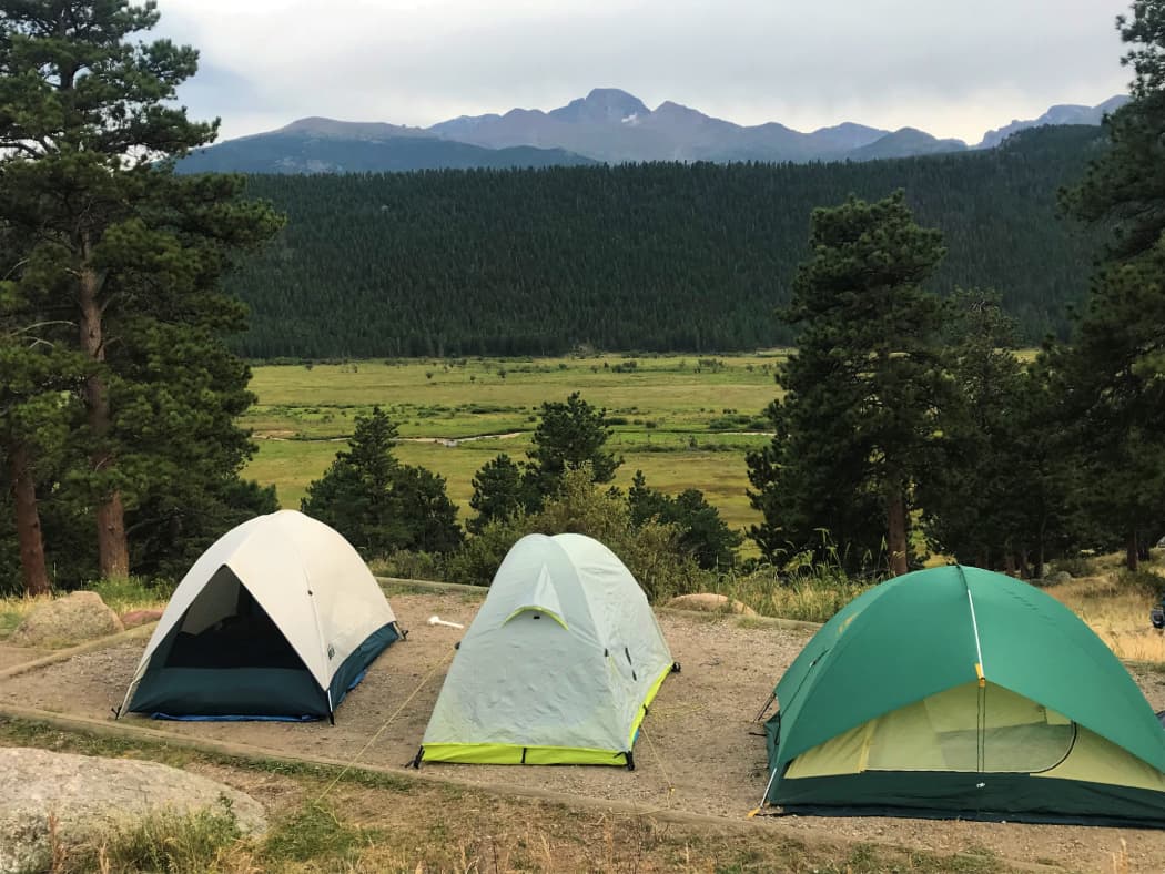 3 small tents on tent pad overlooking pine trees and valley with mountains in the distance
