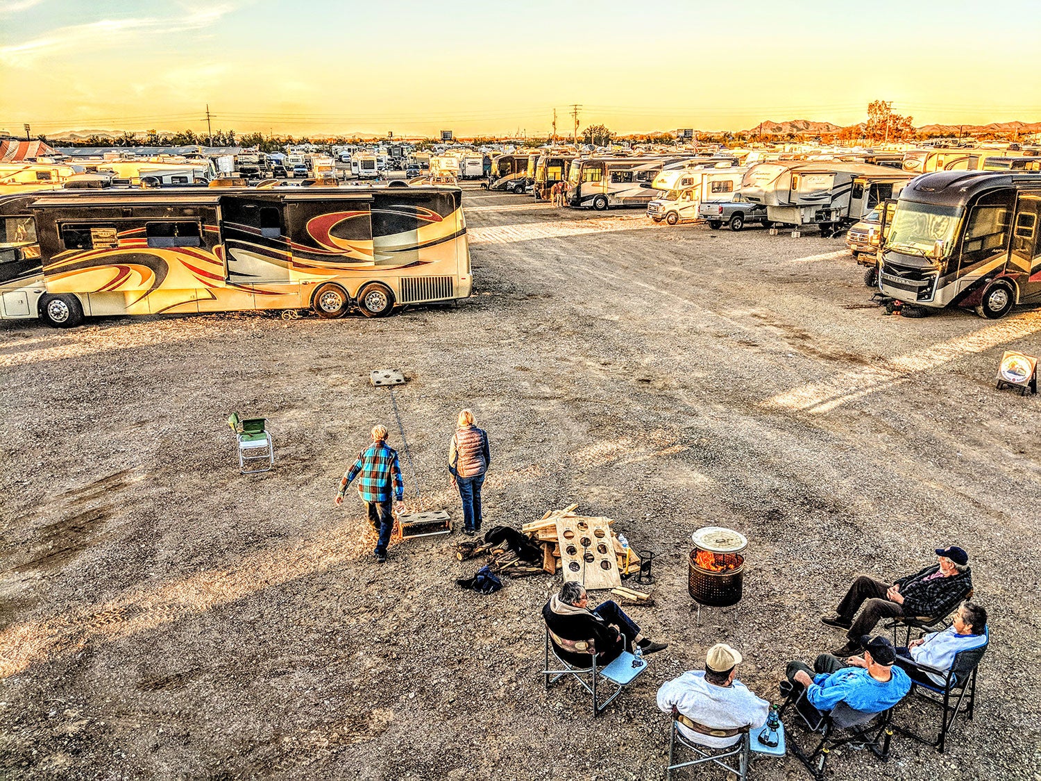 campers play a game on an open field in Quartzsite, AZ near a large field of campervans and RV trailers