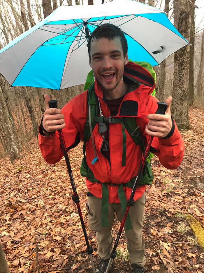 a man smiling wearing a hiking umbrella