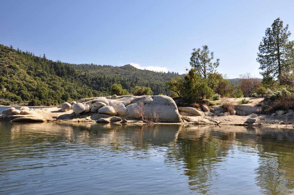 pines trees around outcropping of rocks in lake in southern california mountains